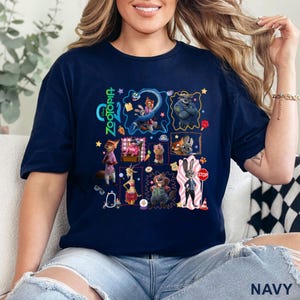 May include: Navy blue t-shirt featuring a colorful graphic of characters from the animated film "Zootopia." The design includes various animal characters in a collage-style arrangement, with the film's title in green and blue. The shirt is a casual wear item.