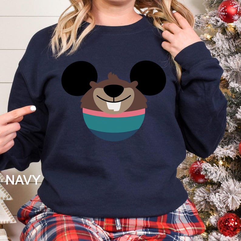 May include: Navy blue sweatshirt featuring a cartoon beaver face with large black ears. The beaver has a brown face, a white tooth, and is wearing a teal and pink striped sweater. The word "NAVY" is printed on the left side.