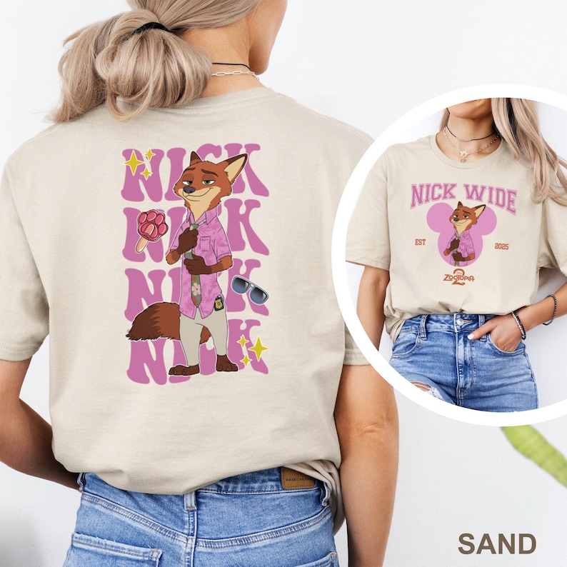 May include: Sand-colored t-shirt featuring a cartoon fox character in a pink shirt and sunglasses. The back of the shirt has the name "Nick" in a stacked design. A smaller image of the same character is on the front.