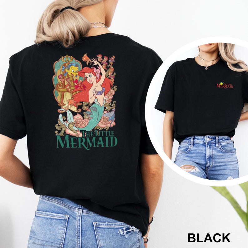 May include: A black t-shirt featuring a large graphic on the back of Ariel from The Little Mermaid surrounded by floral elements and Flounder. The front of the shirt displays a small logo on the chest that reads The Little Mermaid in red text.