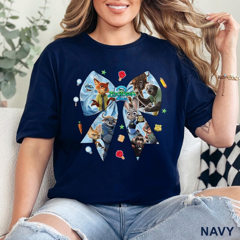 Op de afbeelding: Marineblauw T-shirt met een groot strikdesign met personages uit de film "Zootopia". De strik is gevuld met afbeeldingen van de personages en het woord "Zootopia" staat in het midden. Het shirt is een comfortabele, casual stijl.