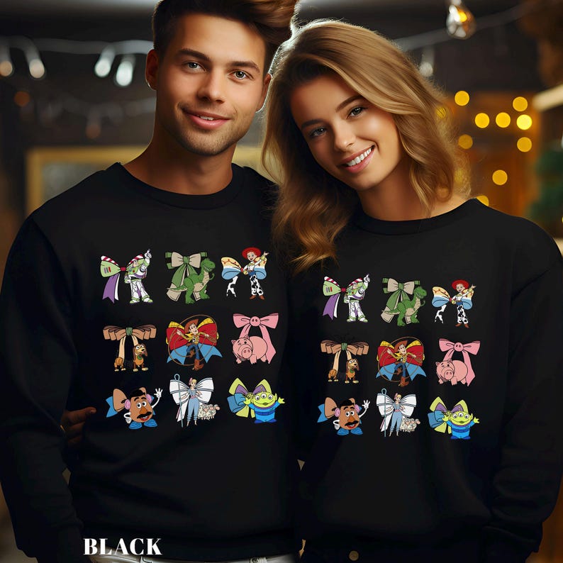 May include: Black sweatshirts featuring colorful cartoon character designs. The designs include characters like Buzz Lightyear, Woody, and others. The word "BLACK" is printed at the bottom of the image.
