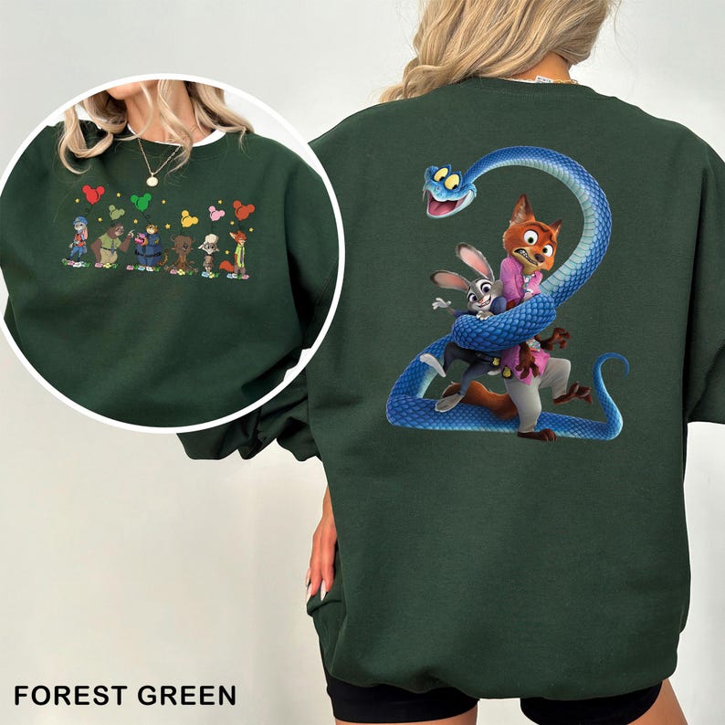 May include: A forest green crewneck sweatshirt featuring a large graphic on the back of a blue snake coiled around a fox and a rabbit. The front chest area displays a smaller graphic of several cartoon characters standing in a row with colorful balloons.
