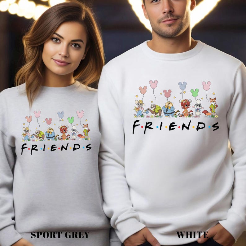 May include: Sport grey and white sweatshirts with a cartoon design featuring characters holding Mickey Mouse-shaped balloons. The word "FRIENDS" is printed in black with colorful dots. The sport grey sweatshirt is labeled "SPORT GREY" and the white sweatshirt is labeled "WHITE".