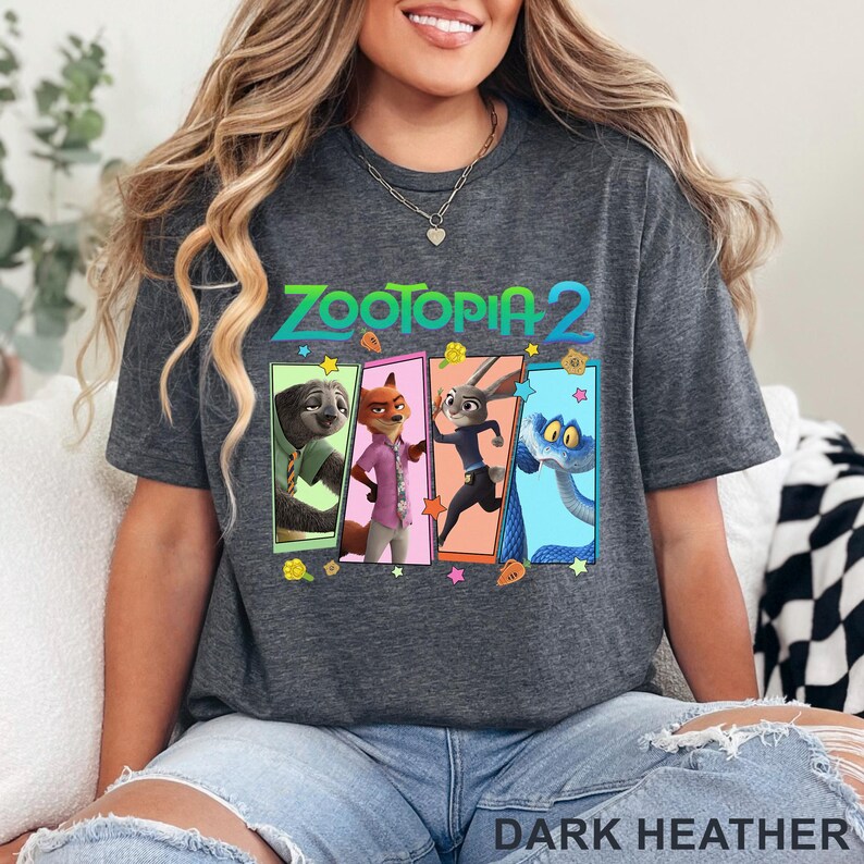 May include: Dark grey t-shirt with the text "ZOOTOPIA 2" and a colourful graphic of characters from the animated film. The graphic includes a sloth, fox, rabbit, and snake. The words "DARK HEATHER" are printed at the bottom.