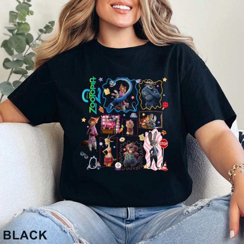 May include: Black t-shirt featuring a colorful graphic of characters from the animated movie "Zootopia." The design includes the movie's title and various character illustrations. The word "BLACK" is printed at the bottom of the shirt.