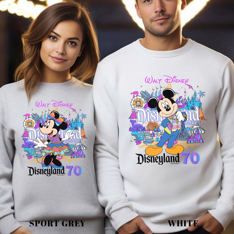 May include: Sport grey and white sweatshirts featuring Mickey and Minnie Mouse with the text "Walt Disney Disneyland 70". The sweatshirts have colorful graphics of amusement park attractions.