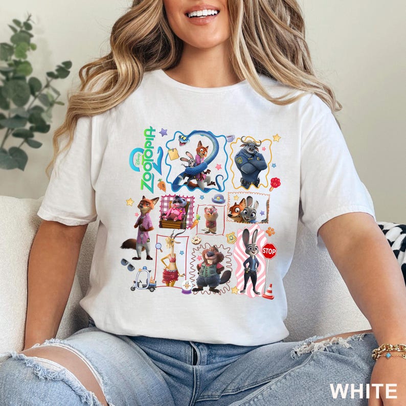 May include: White t-shirt featuring a colorful graphic of characters from the animated movie Zootopia. The design includes various animal characters and the movie's logo. The word "WHITE" is printed at the bottom right.