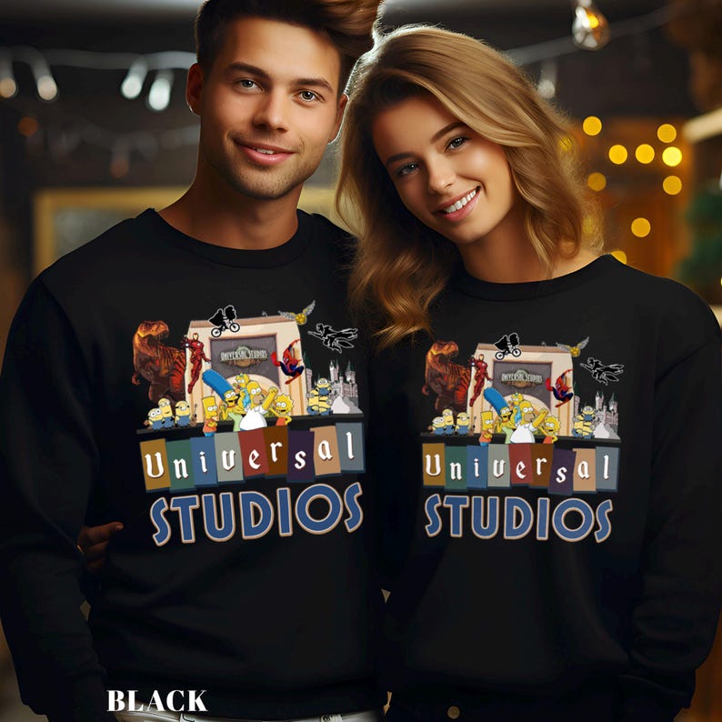 May include: Black crewneck sweatshirts featuring a colorful graphic of Universal Studios characters and the text "UNIVERSAL STUDIOS". The sweatshirts are worn by two people. The word "BLACK" is printed at the bottom.