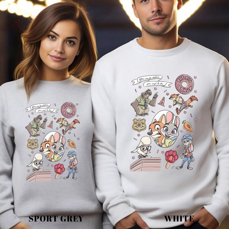 May include: Sport grey and white sweatshirts featuring a colorful cartoon design with various animal characters, including a fox, rabbit, and sloth. The design includes the text "THE BIG DONUT" and other text. The sweatshirts are a crew neck style.