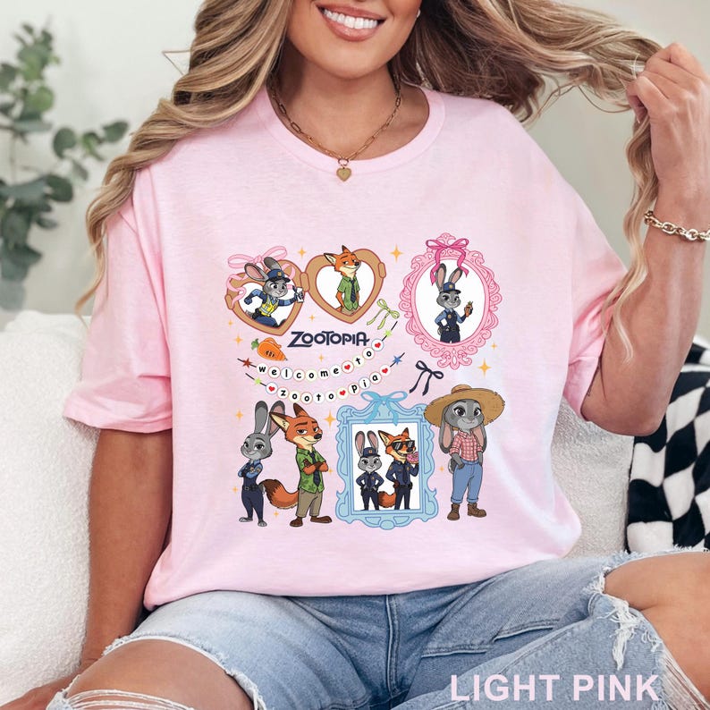 Puede incluir: Una camiseta rosa claro con un estampado gr&aacute;fico de Zootopia que muestra a los personajes Judy Hopps y Nick Wilde. El dise&ntilde;o incluye marcos con forma de coraz&oacute;n y rectangulares, un icono de zanahoria y el texto Welcome to Zootopia.