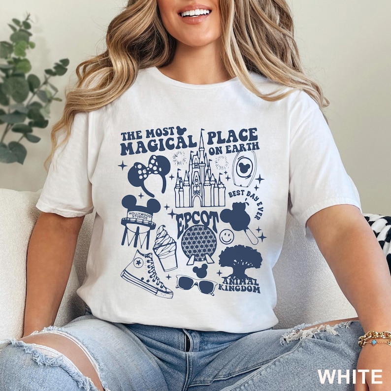 May include: White t-shirt with a navy blue graphic design featuring various Disney icons and the text "THE MOST MAGICAL PLACE ON EARTH." The design includes a castle, Mickey Mouse ears, and other park-related imagery.