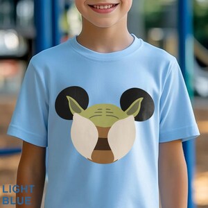 May include: Light blue t-shirt featuring a cartoon design of Yoda with Mickey Mouse ears. The design is in shades of green, brown, and tan, with black ears. The text "LIGHT BLUE" is printed at the bottom left.