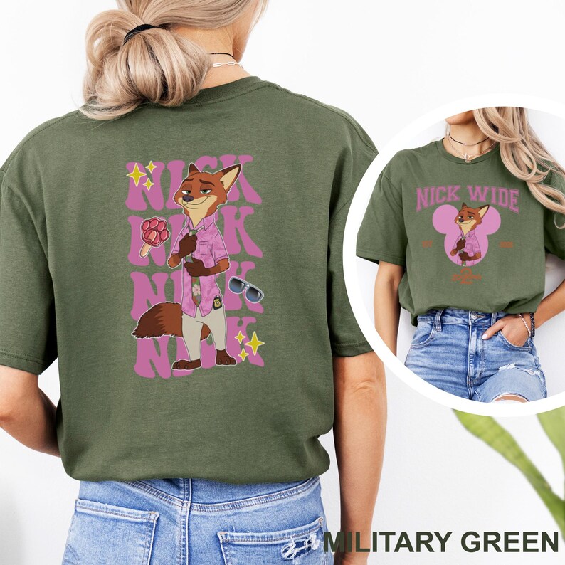 May include: Military green t-shirt featuring a cartoon fox character in a pink shirt and sunglasses. The back of the shirt has the text "Nick" in pink, with a matching graphic. The front of the shirt has the text "Nick Wide".
