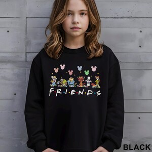May include: Black sweatshirt featuring a colorful graphic of cartoon characters and the word "FRIENDS" in white. Above the characters are Mickey Mouse-shaped balloons in various colors. The word "BLACK" is printed at the bottom right.