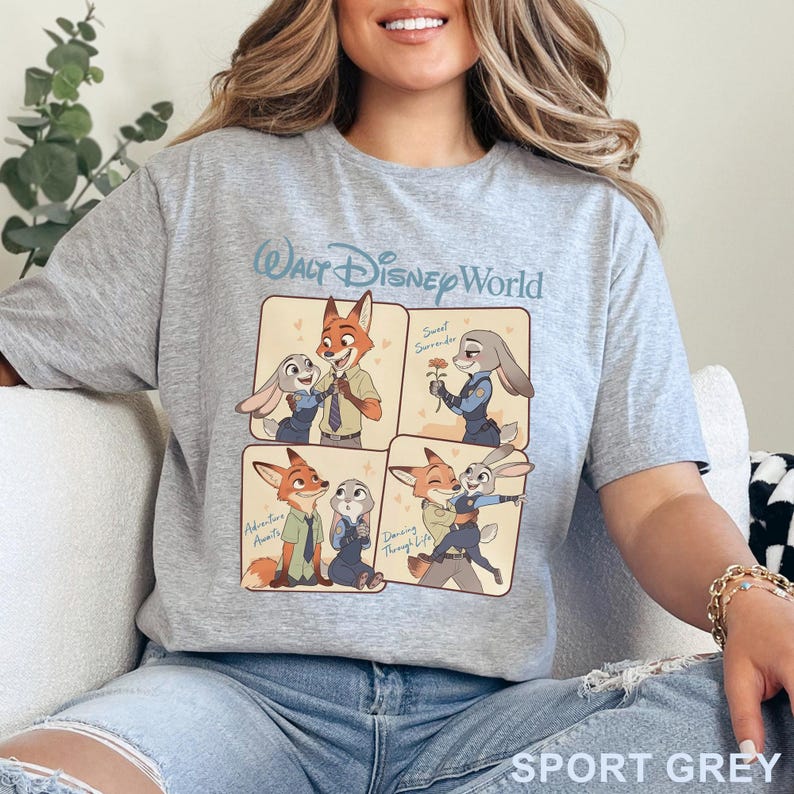 K&ouml;nnte beinhalten: Sportgraues T-Shirt mit einer Cartoon-Grafik von Nick Wilde und Judy Hopps aus Zootopia, mit dem Text "Walt Disney World". Die Grafik ist in vier Felder mit verschiedenen Szenen der Charaktere unterteilt. Das Shirt ist aus weichem Material.