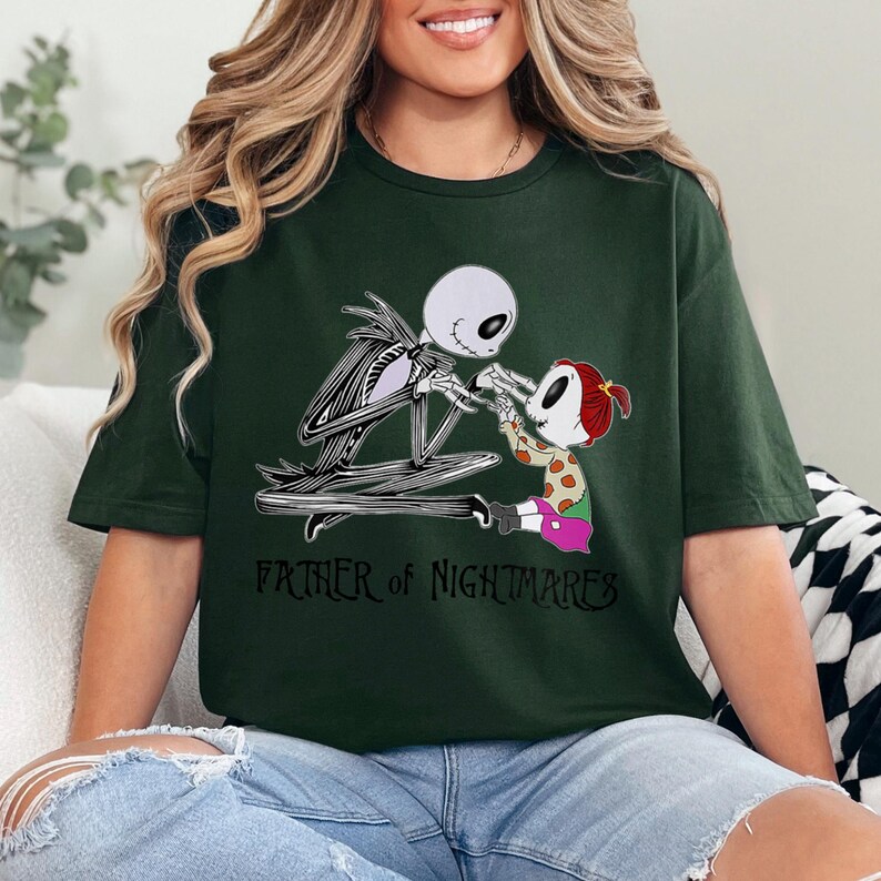 Puede incluir: Camiseta verde oscuro con un gr&aacute;fico de Jack Skellington de Pesadilla antes de Navidad con una figura infantil. El texto "FATHER OF NIGHTMARES" est&aacute; impreso debajo en negro.