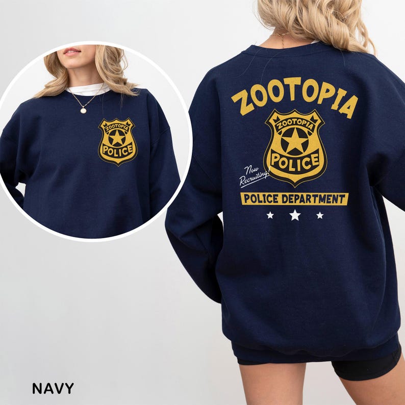 May include: Navy blue sweatshirt featuring a gold and black "Zootopia Police" badge on the front and back. The back also displays the word "Zootopia" and "Police Department" in gold lettering, with three white stars.