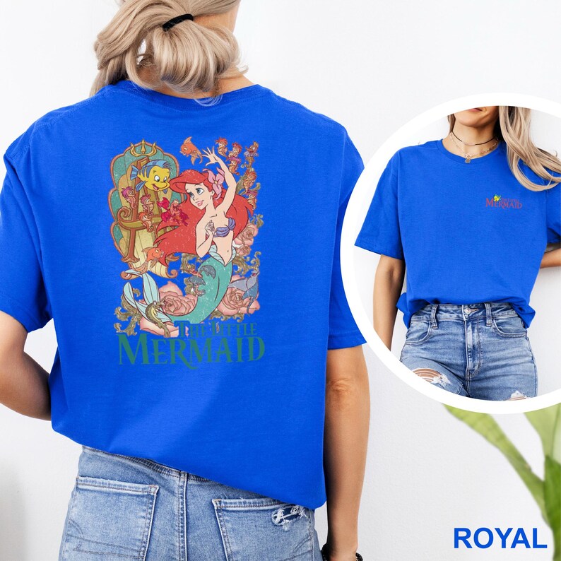 May include: A royal blue short-sleeve t-shirt featuring a large graphic on the back of Ariel and Flounder from The Little Mermaid surrounded by floral elements. The front chest area displays a small logo with the text The Little Mermaid.