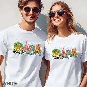 May include: Two white short-sleeved t-shirts featuring a colorful graphic print of the Walt Disney World theme park landmarks, including a castle, a geodesic sphere, and a tower, with the text Walt Disney World in a stylized blue script font.