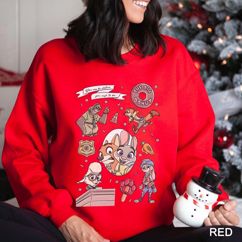 May include: A red sweatshirt featuring cartoon characters and the text "The Big Donut." The design includes a police badge, a carrot, and the phrase "You can be whatever you wish to be." The sweatshirt is a festive holiday item.