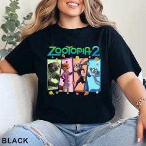 May include: Black t-shirt with the text "ZOOTOPIA 2" in green and blue. The design includes four cartoon characters in colourful rectangular frames. The word "BLACK" is printed at the bottom of the image.
