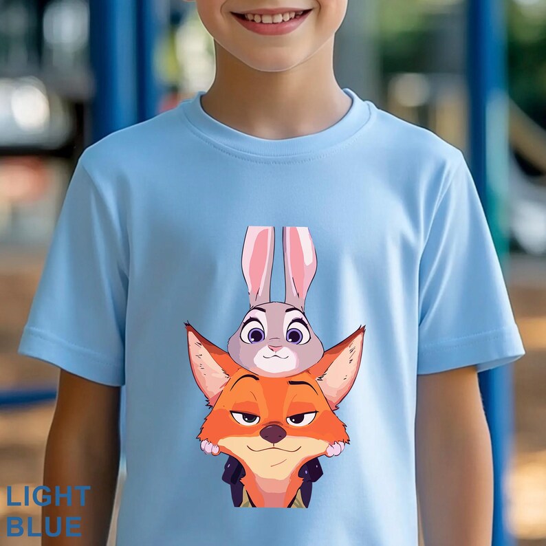 May include: Light blue t-shirt featuring a cartoon illustration of Judy Hopps the bunny and Nick Wilde the fox from Zootopia. The text "LIGHT BLUE" is printed in blue at the bottom left of the shirt.
