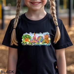 May include: A black short-sleeved t-shirt featuring a colorful graphic print of the Walt Disney World theme park landmarks, including a large tree, a pink castle, a geodesic dome, and a tower, with the text Walt Disney World in blue script.