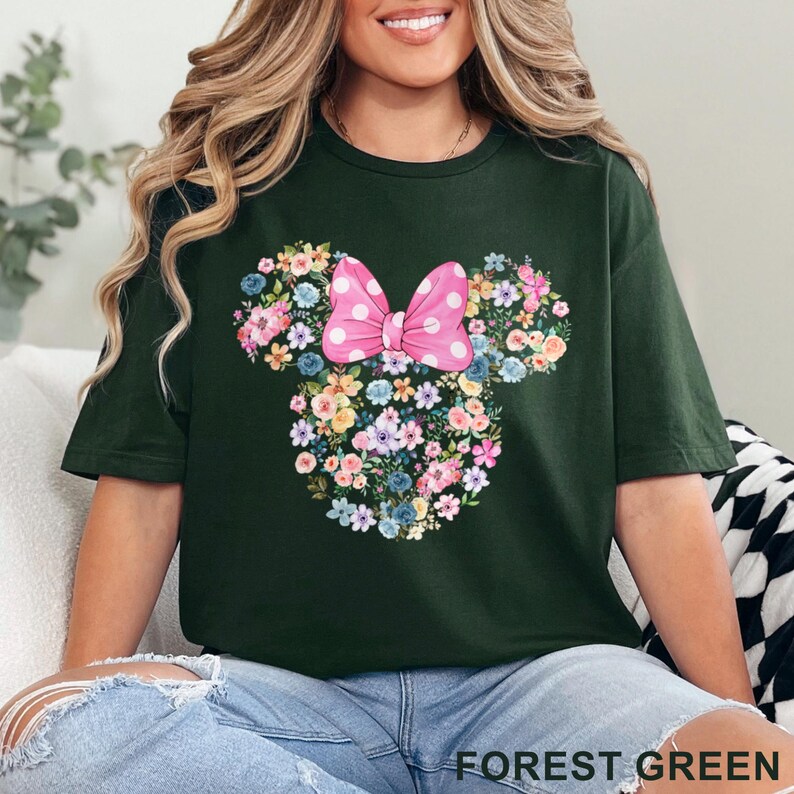 May include: Forest green t-shirt featuring a floral Mickey Mouse design with a pink polka dot bow. The design is made of various colorful flowers. The text "FOREST GREEN" is at the bottom of the image.