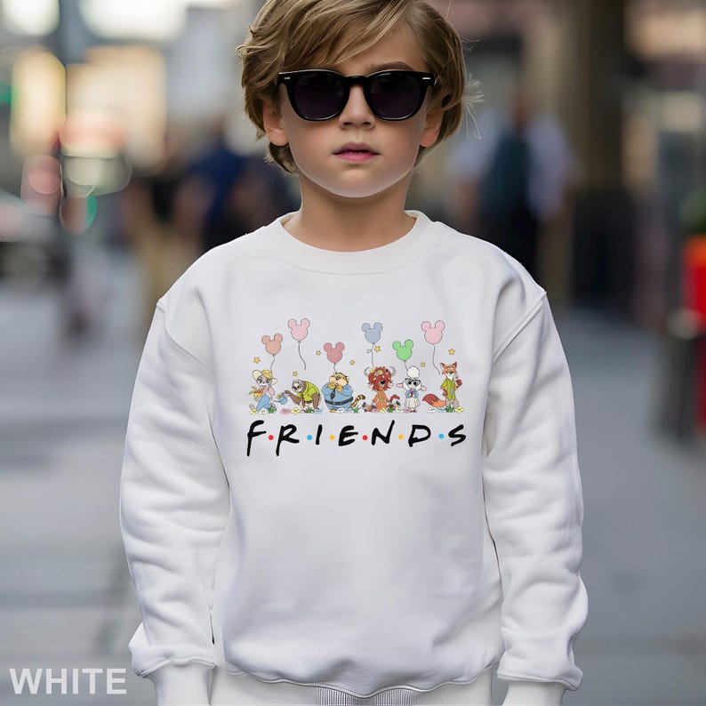 May include: White sweatshirt featuring a colorful graphic of cartoon animals holding balloons above the word "FRIENDS" in black. The sweatshirt is made of a soft material and is suitable for casual wear.
