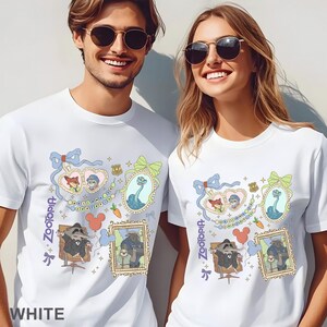 Puede incluir: Camisetas blancas con un dise&ntilde;o colorido de Zootopia. El dise&ntilde;o incluye retratos de personajes enmarcados, lazos y la palabra "Zootopia". Las camisetas son usadas por dos personas.