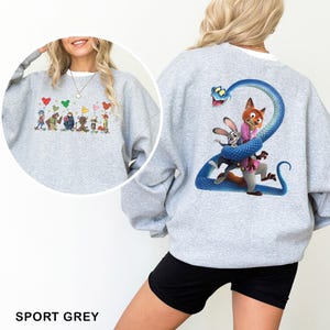 May include: A sport grey crewneck sweatshirt featuring a large graphic on the back of a blue snake coiled around a rabbit and a fox character. The front chest area displays a smaller graphic of multiple animated characters holding colorful balloons.