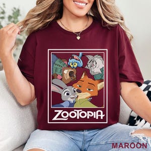 May include: A maroon t-shirt with a Zootopia graphic. The design features characters from the animated film, including Judy Hopps and Nick Wilde, and the film's title in white. The word "MAROON" is printed at the bottom of the shirt.