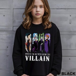 Puede incluir: Sudadera negra con un gr&aacute;fico de cuatro villanos de dibujos animados y el texto "Sweetie I'm OK with being the Villain". El gr&aacute;fico incluye a Cruella de Vil, &Uacute;rsula, Mal&eacute;fica y la Reina Malvada. La palabra "BLACK" est&aacute; impresa en la parte inferior derecha.