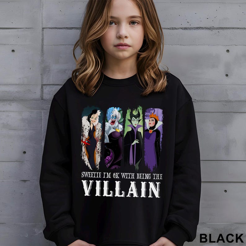 Puede incluir: Sudadera negra con un gr&aacute;fico de cuatro villanos de dibujos animados y el texto "Sweetie I'm OK with being the Villain". El gr&aacute;fico incluye a Cruella de Vil, &Uacute;rsula, Mal&eacute;fica y la Reina Malvada. La palabra "BLACK" est&aacute; impresa en la parte inferior derecha.