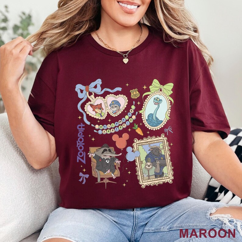 Puede incluir: Camiseta granate con ilustraciones enmarcadas de personajes de Zootopia. La camiseta incluye la palabra "Zootopia" en fuente vertical. Las ilustraciones est&aacute;n rodeadas de lazos, corazones y un collar de perlas. La palabra "MAROON" est&aacute; impresa en la parte inferior.