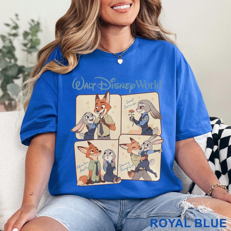 K&ouml;nnte beinhalten: K&ouml;nigsblaues T-Shirt mit einem Cartoon-Design mit Charakteren aus Zootopia. Das Design enth&auml;lt den Text "Walt Disney World" und vier Panels mit Bildern der Charaktere. Das Shirt hat eine einfarbige k&ouml;nigsblaue Farbe.