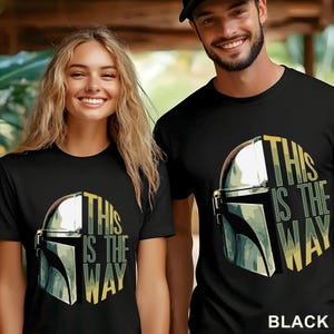 Pu&ograve; includere: Una t-shirt nera a maniche corte con la grafica di un casco metallico e la scritta "THIS IS THE WAY" in un motivo mimetico giallo e verde. Il design &egrave; centrato sul petto del capo d'abbigliamento realizzato in tessuto di colore nero.