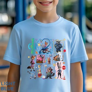 May include: Light blue t-shirt featuring a colorful graphic of characters from the animated movie "Zootopia." The design includes various animal characters and the movie's title. The shirt also has the words "LIGHT BLUE" printed on it.