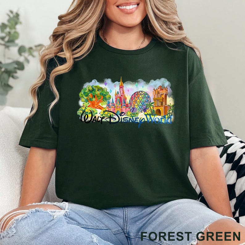 May include: A forest green short-sleeve t-shirt featuring a colorful graphic print of the Walt Disney World theme park landmarks, including the castle, the geodesic sphere, and a large tree, with the text Walt Disney World printed in blue.