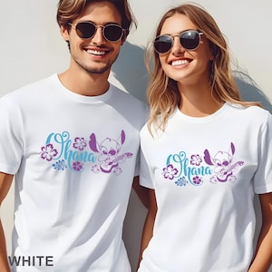 Op de afbeelding: Twee witte T-shirts met korte mouwen en een grafische print van het personage Stitch die op een ukelele speelt. Het ontwerp bevat het woord Ohana in een blauwgroen cursief lettertype, omringd door paarse en blauwgroene hibiscusbloemen.