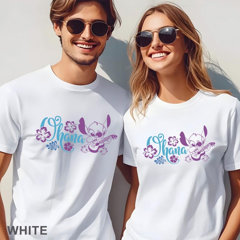 Op de afbeelding: Twee witte T-shirts met korte mouwen en een grafische print van het personage Stitch die op een ukelele speelt. Het ontwerp bevat het woord Ohana in een blauwgroen cursief lettertype, omringd door paarse en blauwgroene hibiscusbloemen.