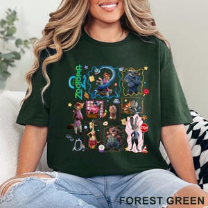 May include: Forest green t-shirt featuring a colorful graphic of characters from the animated movie Zootopia. The design includes various animal characters in a collage-style arrangement, with the word "Zootopia" in green. The shirt is made of a soft material.