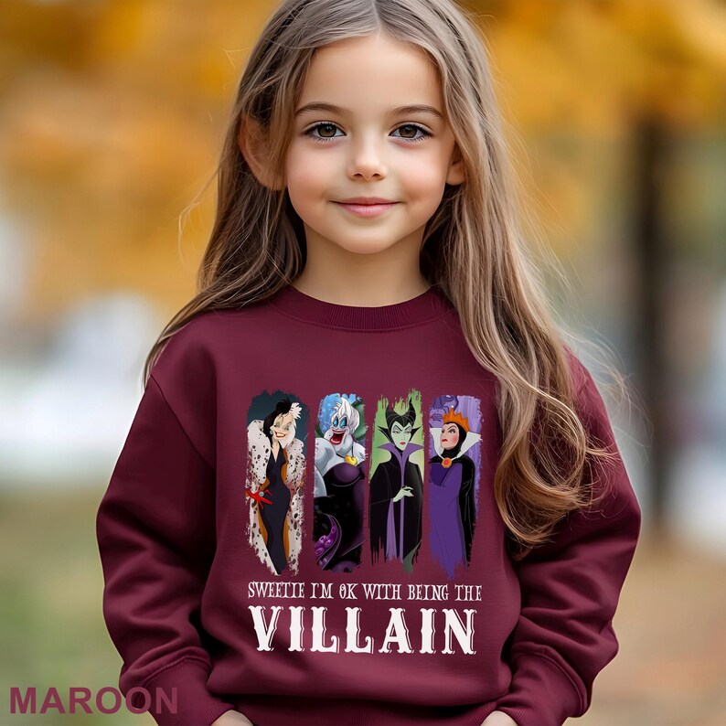 Puede incluir: Una sudadera burdeos con un estampado de cuatro villanos de dibujos animados y el texto "Sweetie I'm OK with being the Villain". La sudadera es de cuello redondo.