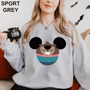 May include: Sport grey sweatshirt featuring a cartoon beaver design with large black ears, a brown face, and a blue and pink striped body. The sweatshirt has the words "SPORT GREY" printed at the top.