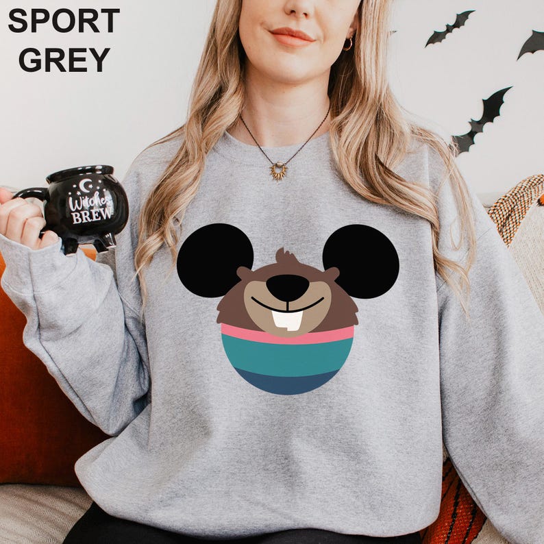 May include: Sport grey sweatshirt featuring a cartoon beaver design with large black ears, a brown face, and a blue and pink striped body. The sweatshirt has the words "SPORT GREY" printed at the top.