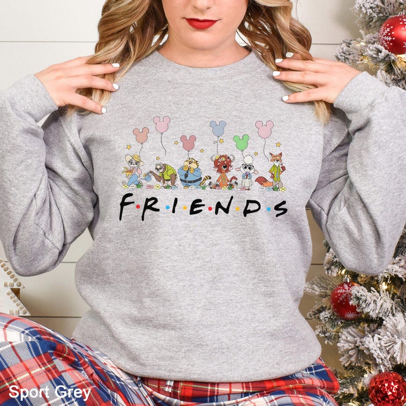 May include: A light gray sweatshirt featuring the word "FRIENDS" in a black font. Above the word are cartoon characters holding Mickey Mouse-shaped balloons. The sweatshirt is a long-sleeved crew neck.