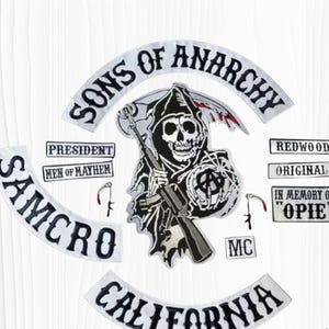 May include: A collection of embroidered patches featuring the "Sons of Anarchy" theme. The patches include the Grim Reaper with a scythe, the words "Sons of Anarchy," "Samcro," "California," and other text. The patches are in black and white.