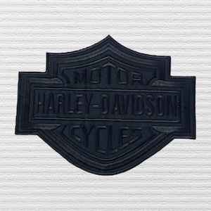 May include: Black Harley-Davidson Cycles patch with raised lettering and a textured surface. The patch features the Harley-Davidson logo in a shield shape, with the words "MOTOR HARLEY-DAVIDSON CYCLES".