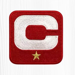 May include: Embroidered patch featuring a large white "C" on a red square background. A small gold star is embroidered below the letter. The patch has a stitched border.